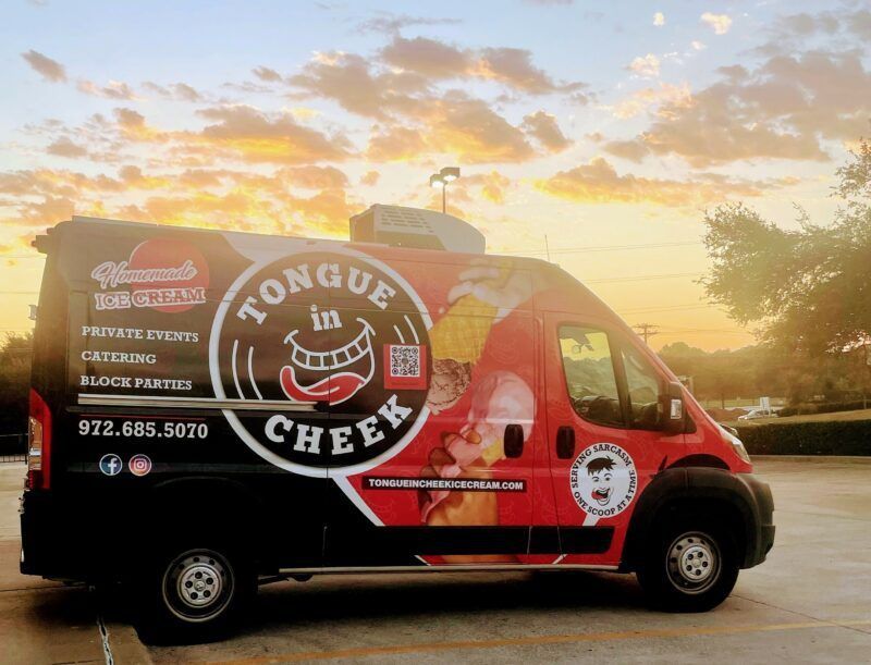 A tongue in cheek food truck is parked in a parking lot