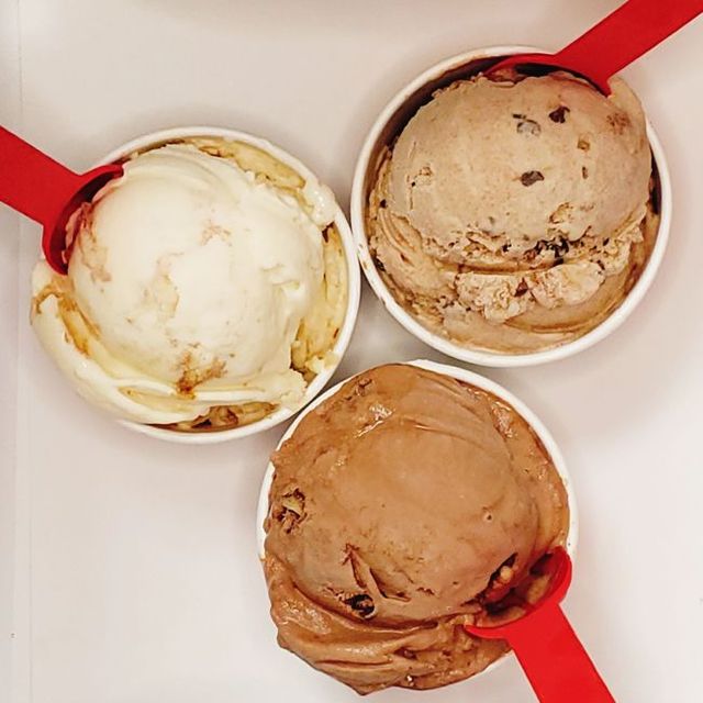 Three cups of ice cream with red spoons in them