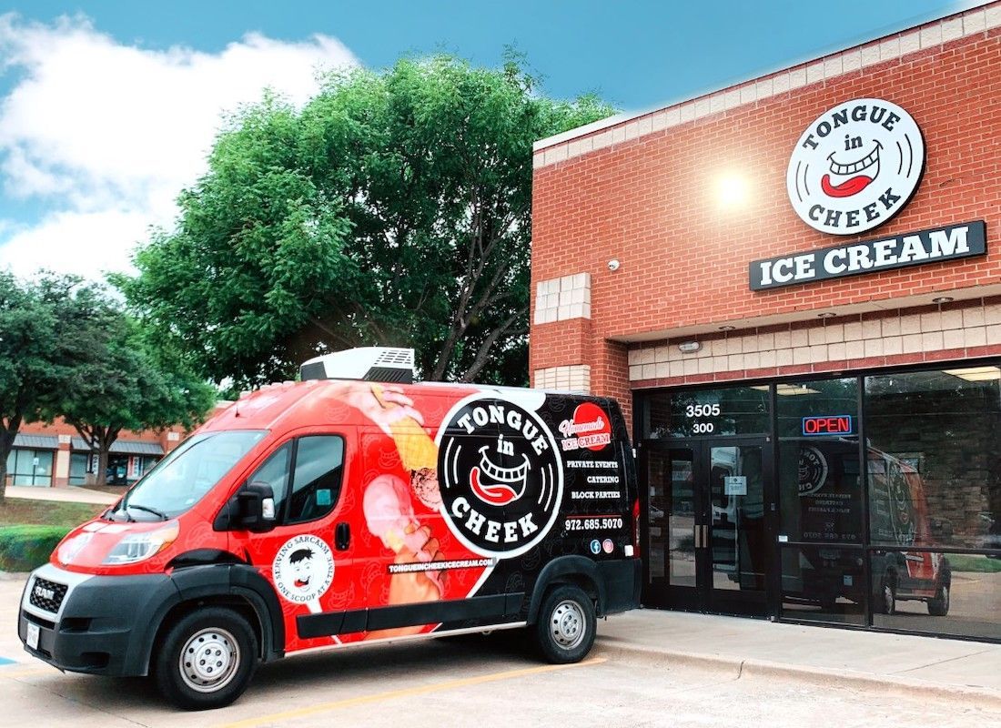A red van is parked in front of an ice cream shop.