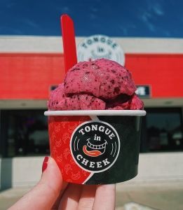A person is holding a cup of ice cream in front of a store.