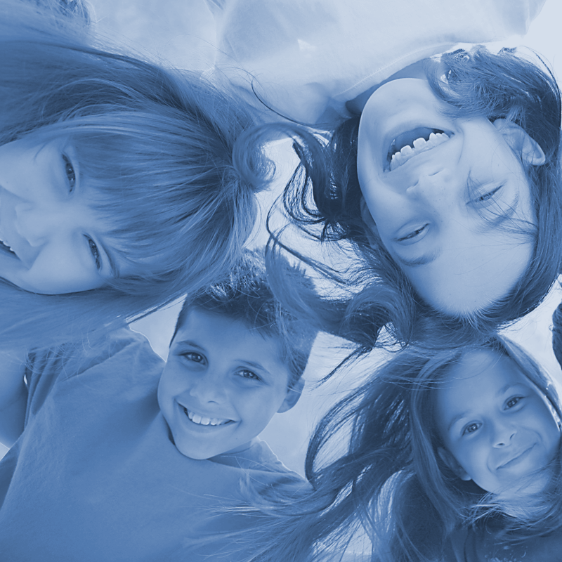 A group of children are laying upside down in a circle and smiling
