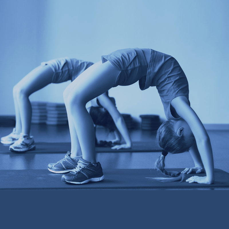 Two girls are doing a handstand on a yoga mat