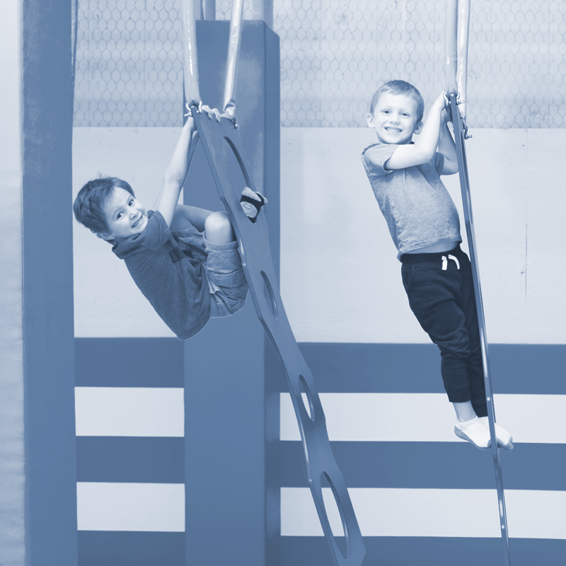 Two young boys are playing on a monkey bars