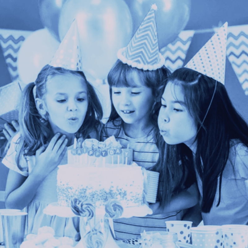 Three little girls are blowing out candles on a birthday cake.