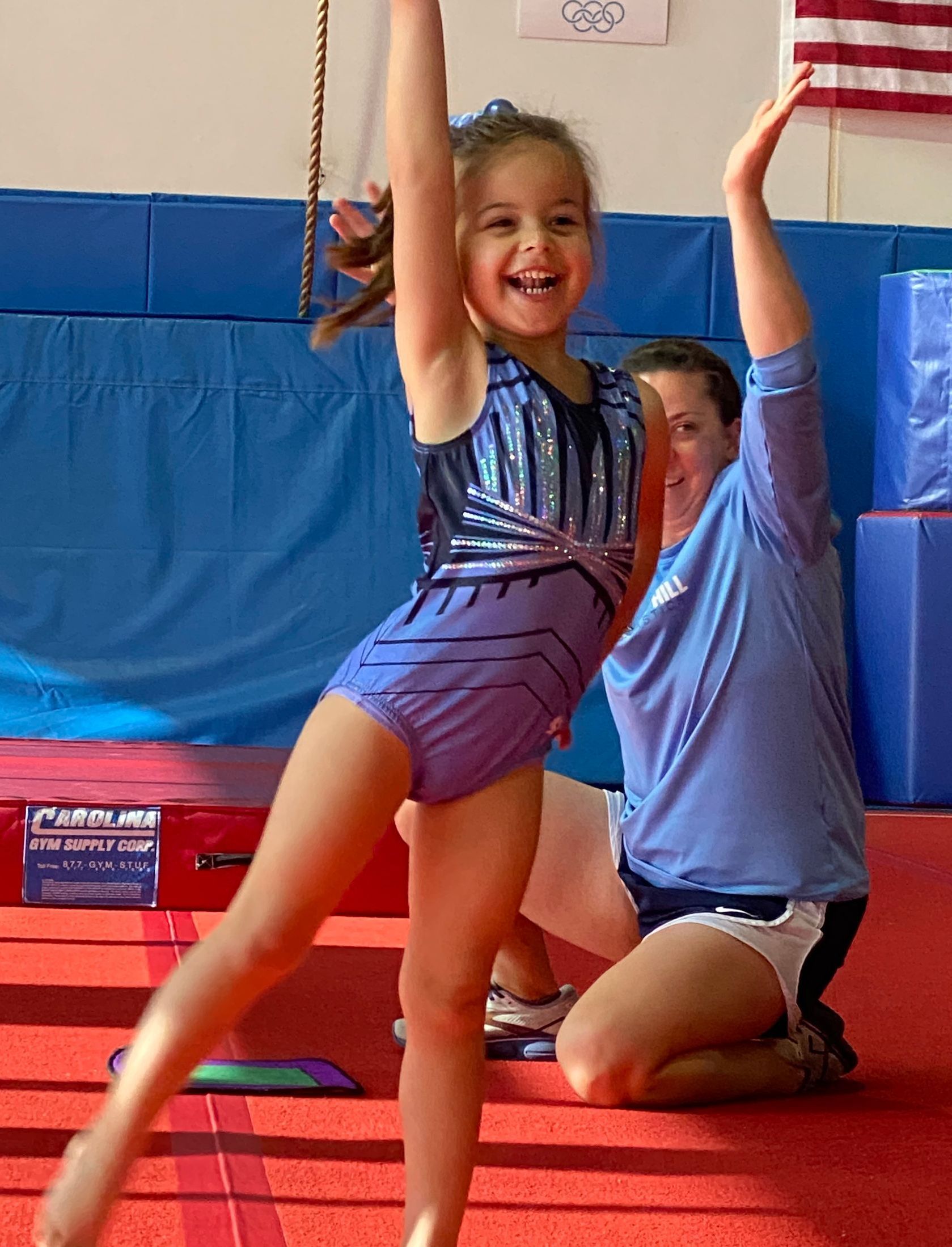 A young boy is doing a handstand on a mat in a gym.