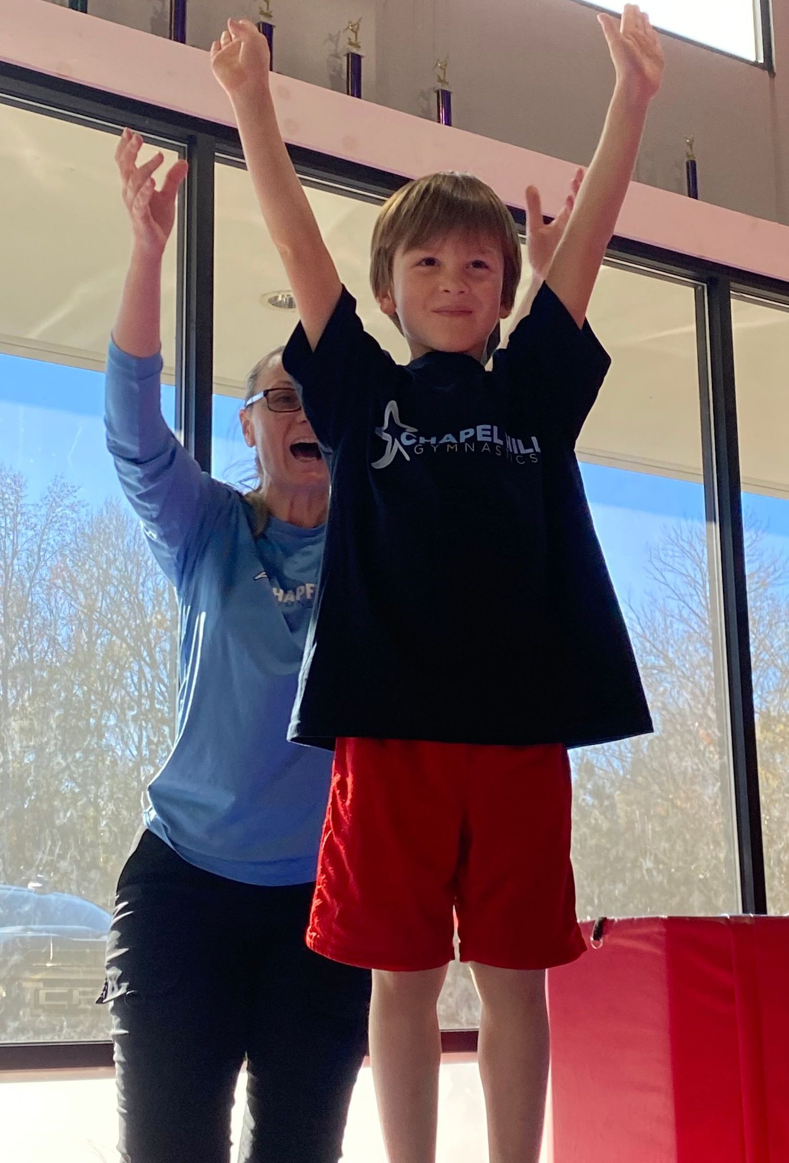 A woman is helping a young boy balance on a balance beam.