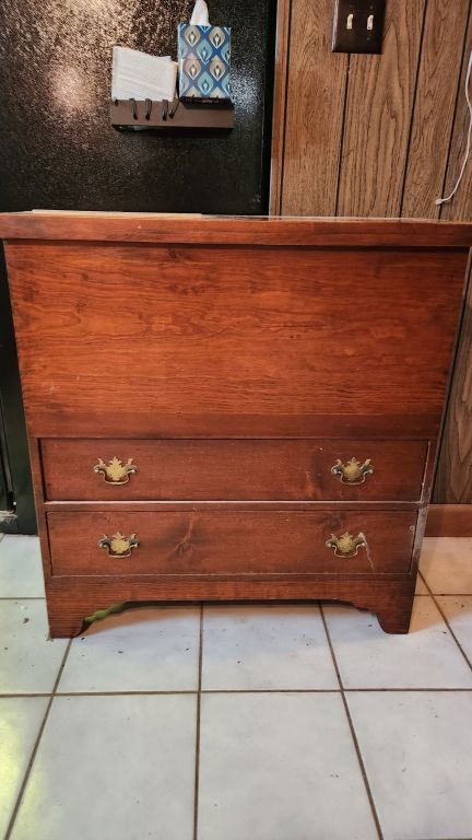 Wooden chest of drawers with two brass-handled drawers on a white tiled floor indoors