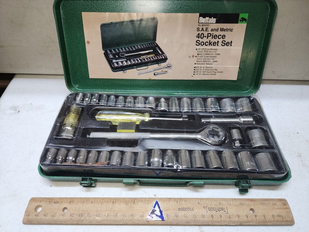 Green metal socket set case open with wrench and assorted sockets, ruler below for scale