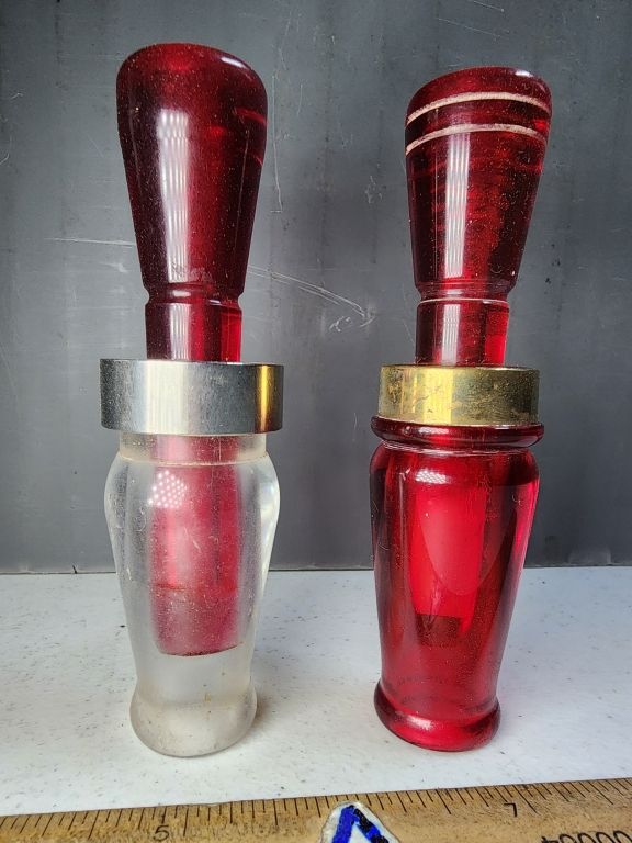 Two red glass perfume bottles with silver and gold bands, standing side by side on a gray surface.