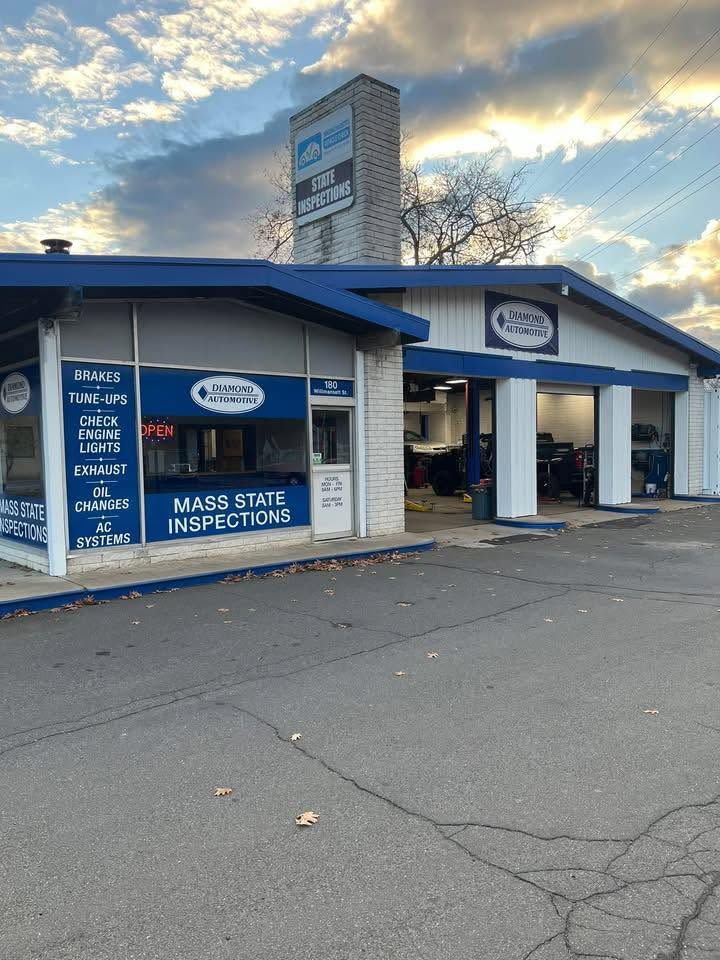 Blue auto service signage and garage bays under a cloudy sky | Diamond Automotive