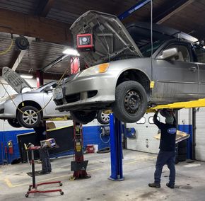 Auto repair shop with cars lifted on hydraulic lifts while mechanics work underneath and inspect engines | Diamond Automotive
