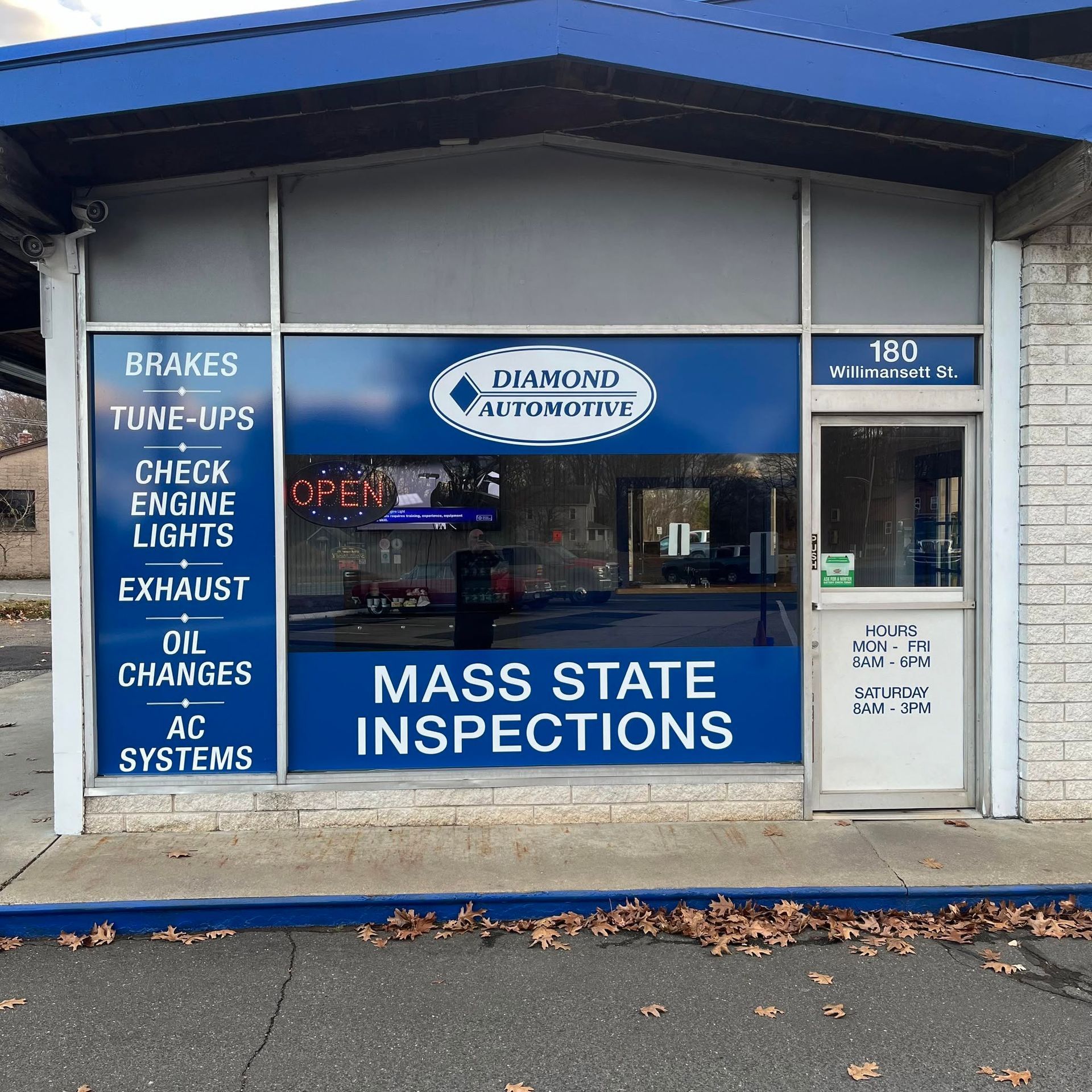 Blue auto repair shop storefront with sign and service listings on windows | Diamond Automotive
