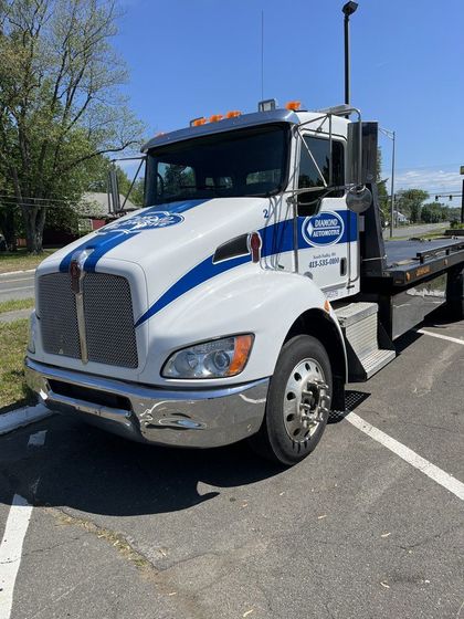 White tow truck with blue stripes parked in a lot on a sunny day | Diamond Automotive