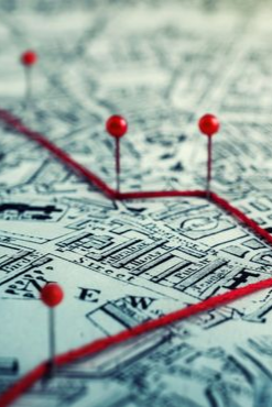Map with red pins connected by red string, tracing a route.