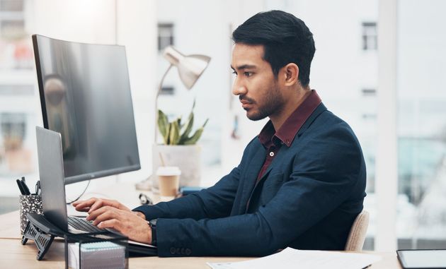 Person typing at a desktop computer in a bright office, focused on work.