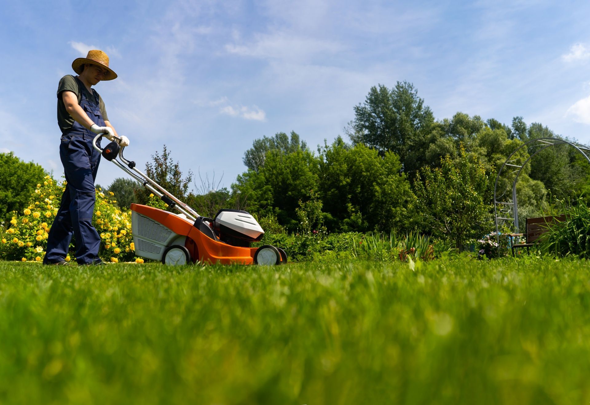 A man is cutting the grass with a lawn mower.