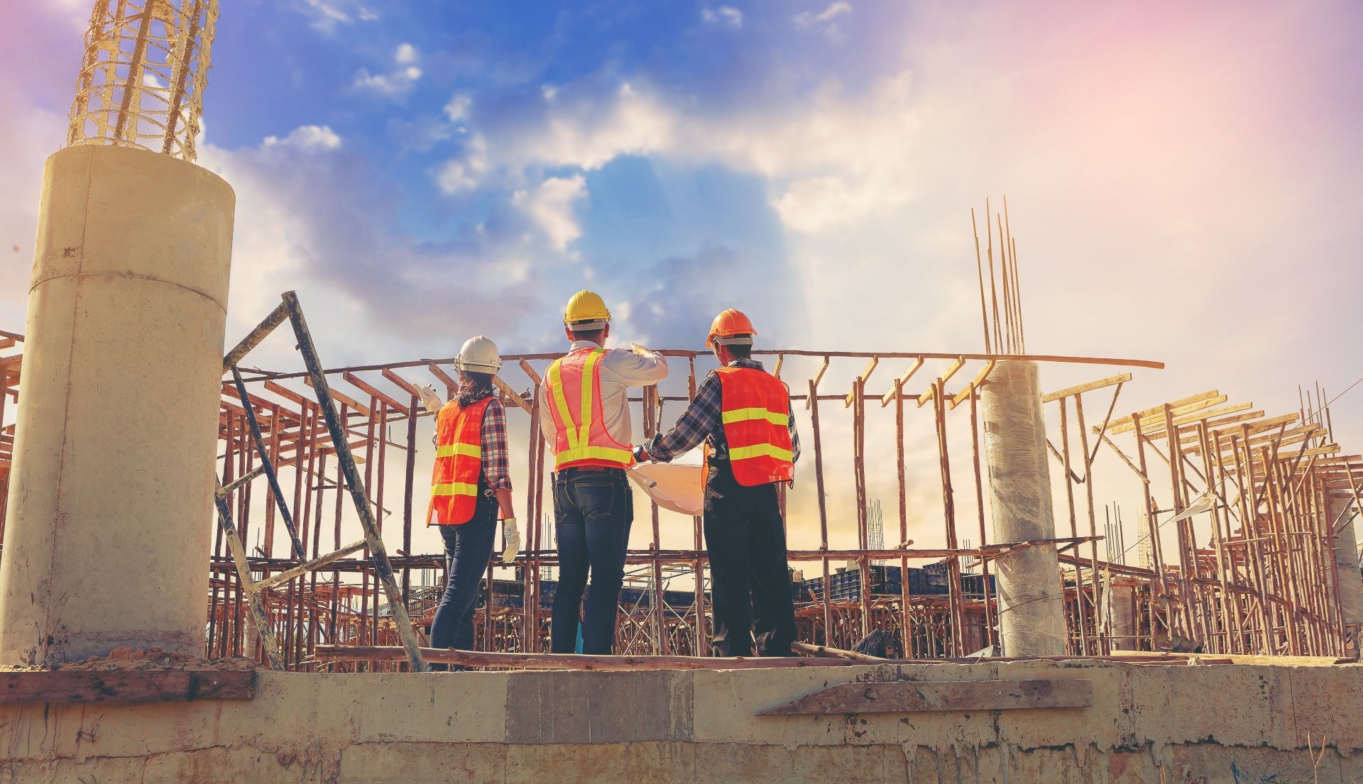 A group of construction workers are standing on top of a building under construction.