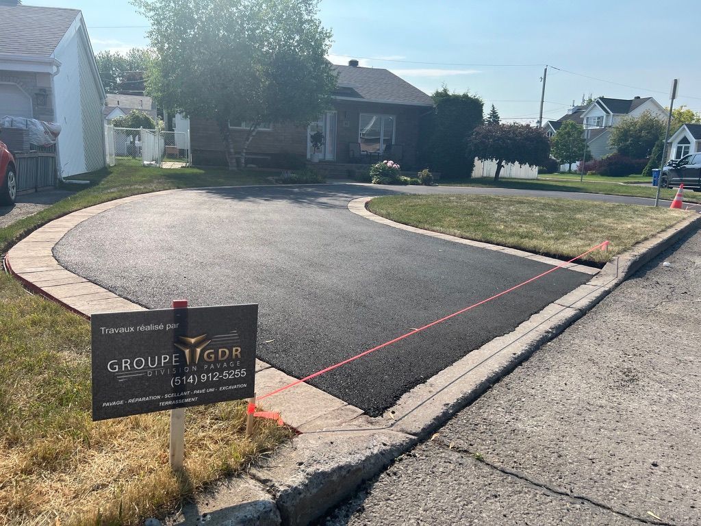 Allée asphaltée récemment pavée, bordée de pierres, devant une maison. Panneau « Groupe York » au premier plan.