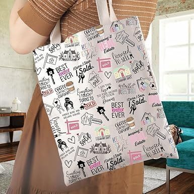 White tote bag with black-and-pink text and doodle print, held by a person indoors