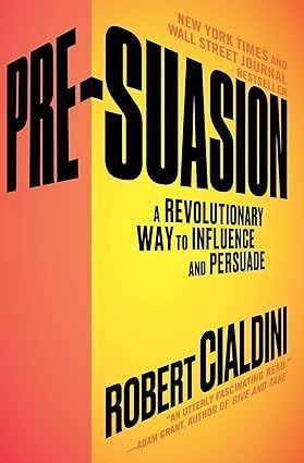 Book cover of “Pre-Suasion” by Robert Cialdini, with bold black and yellow text on a pink-orange background