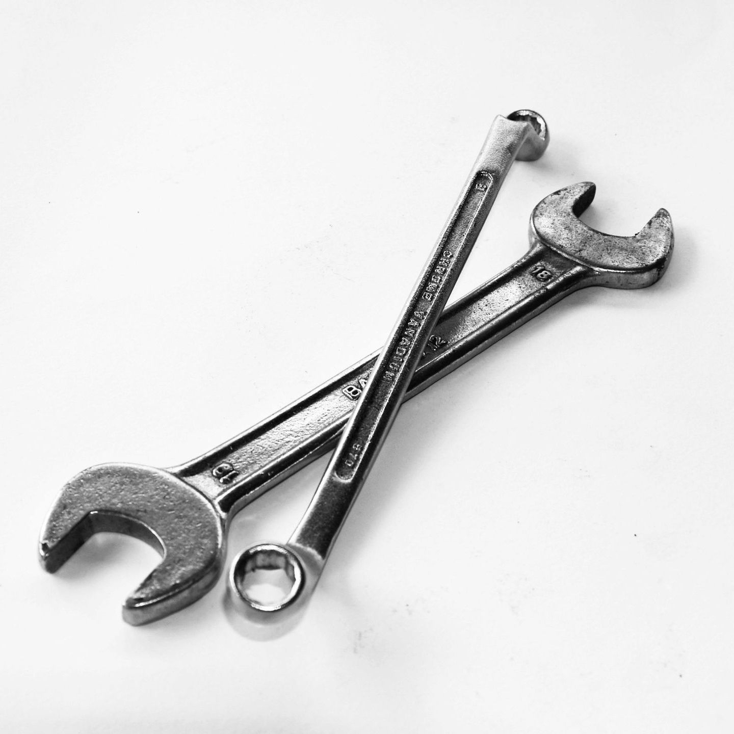 Two silver wrenches crossed on a white background