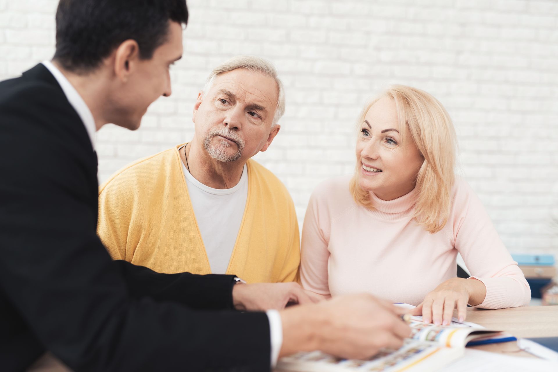 A man in a suit speaks with an older couple, representing customized estate planning in Washington.
