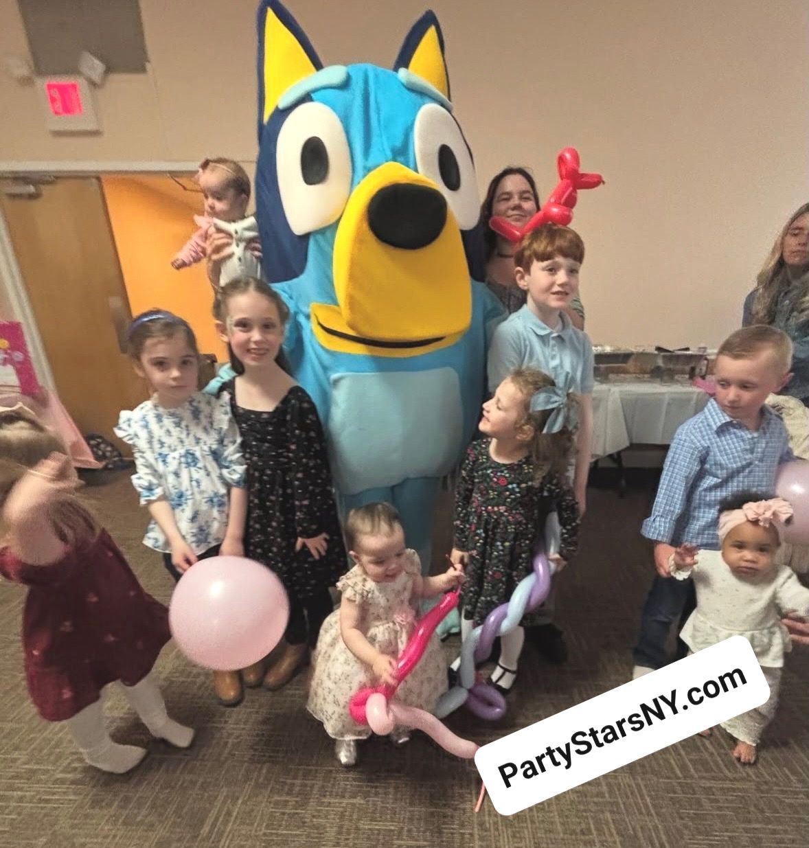 A group of children standing around a blue dog mascot
