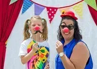 A woman and a little girl are posing for a picture in a clown costume.