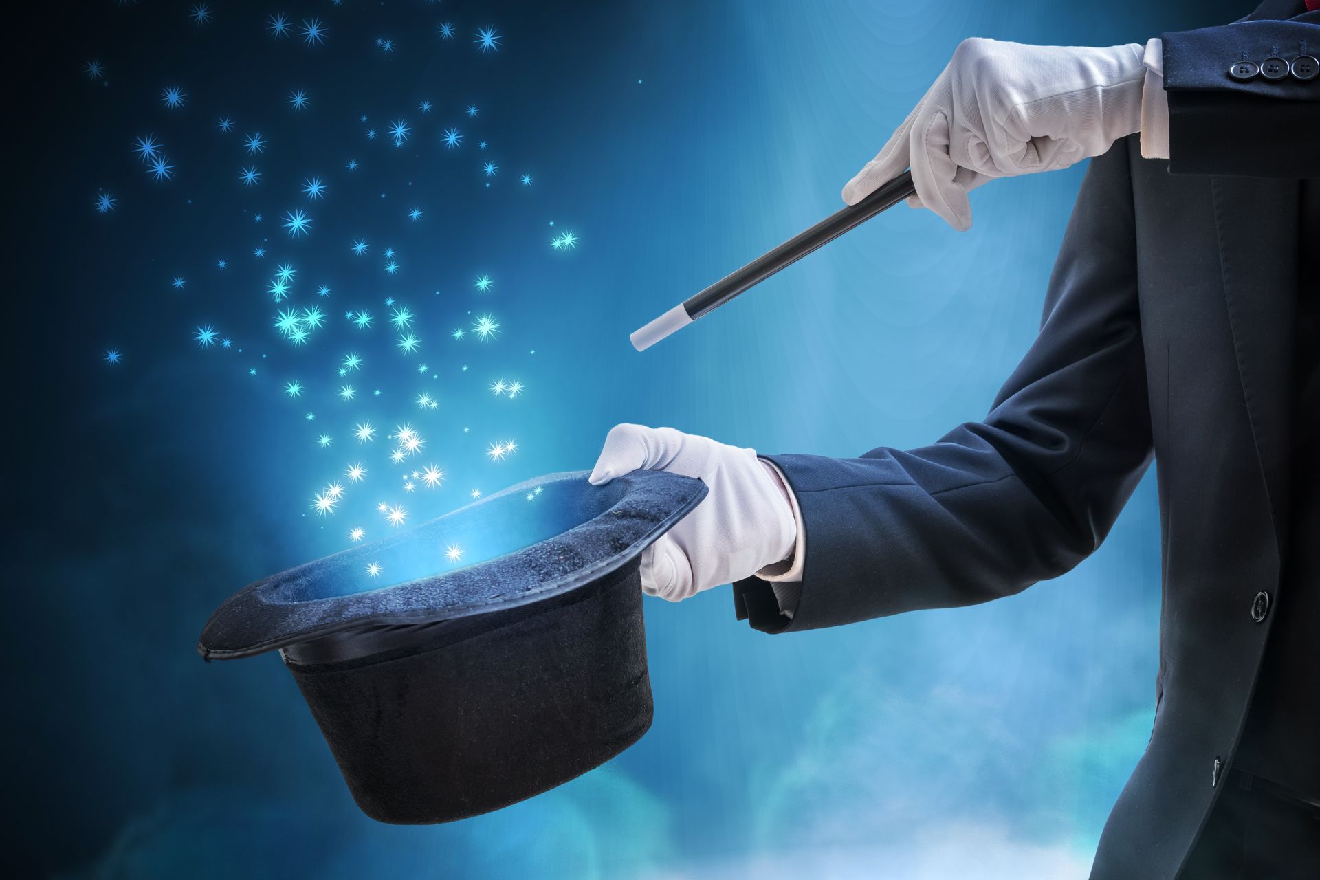 A man in a suit and white gloves is holding a magic wand and a top hat.