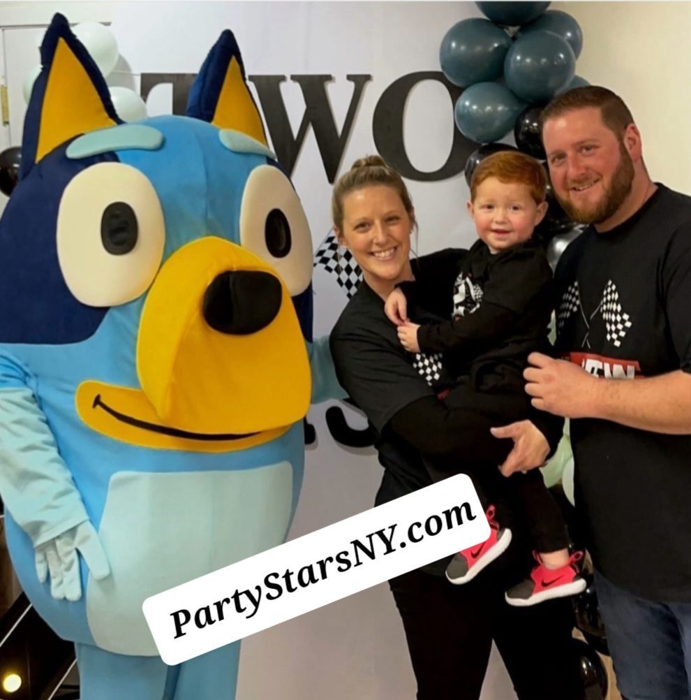 A woman holding a child next to a blue dog mascot