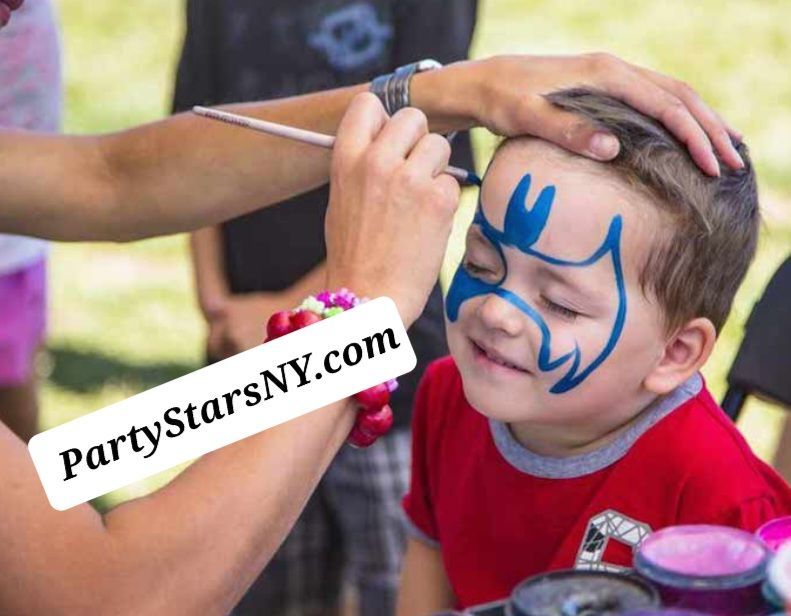 A little boy is getting his face painted with the website partystarsny.com