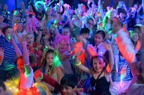 A group of children are dancing at a glow in the dark party.