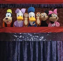 A group of stuffed disney characters are sitting on top of a stage.