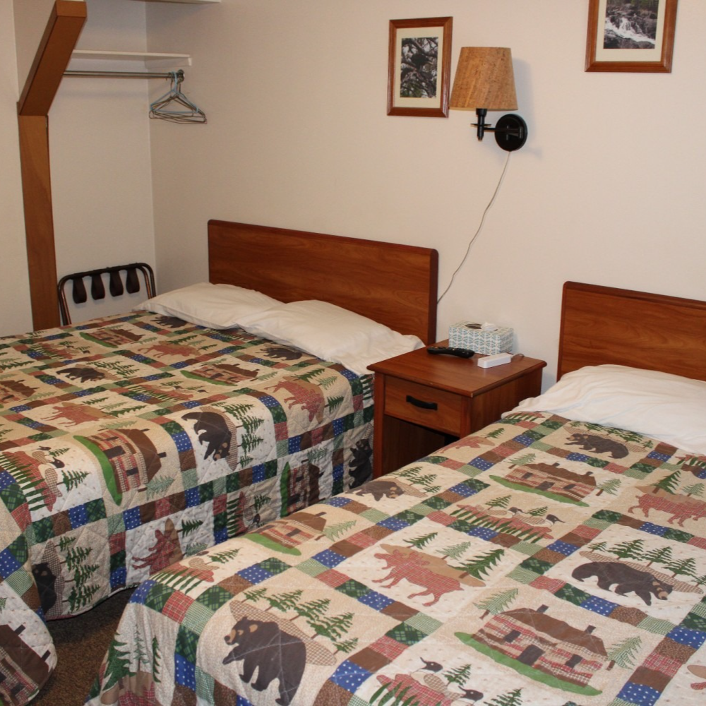 Hotel room with two twin beds, patterned quilts, and a nightstand between them