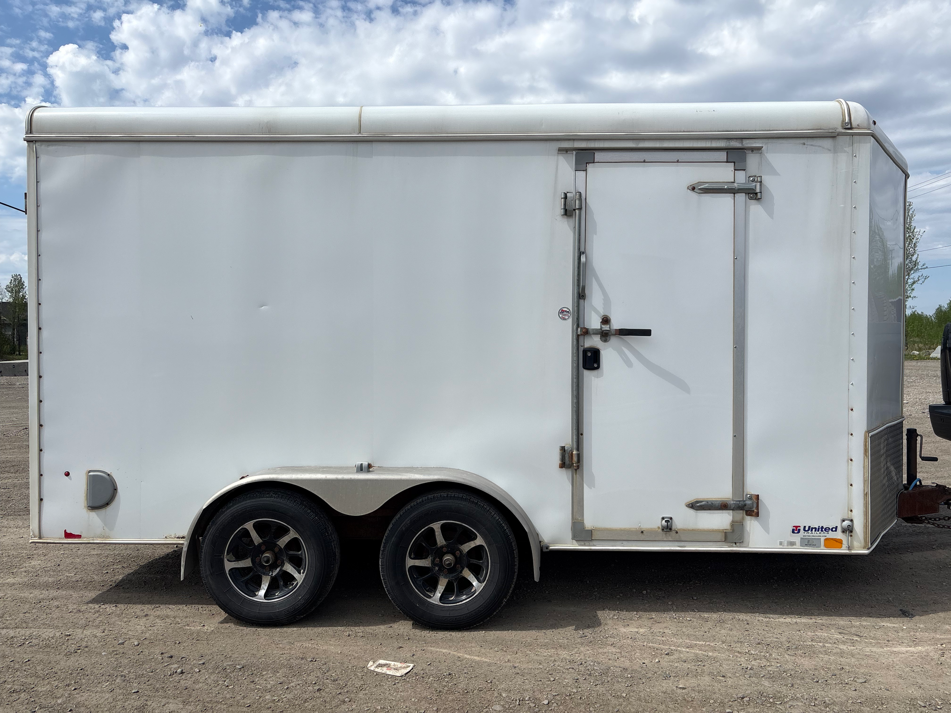 Car trailer with ramps on gravel.