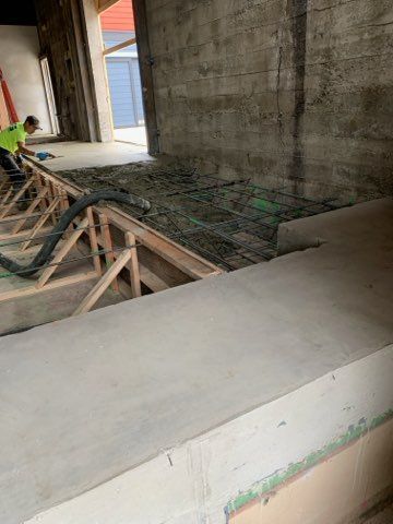 Construction worker pouring wet concrete onto rebar from a chute in a foundation site