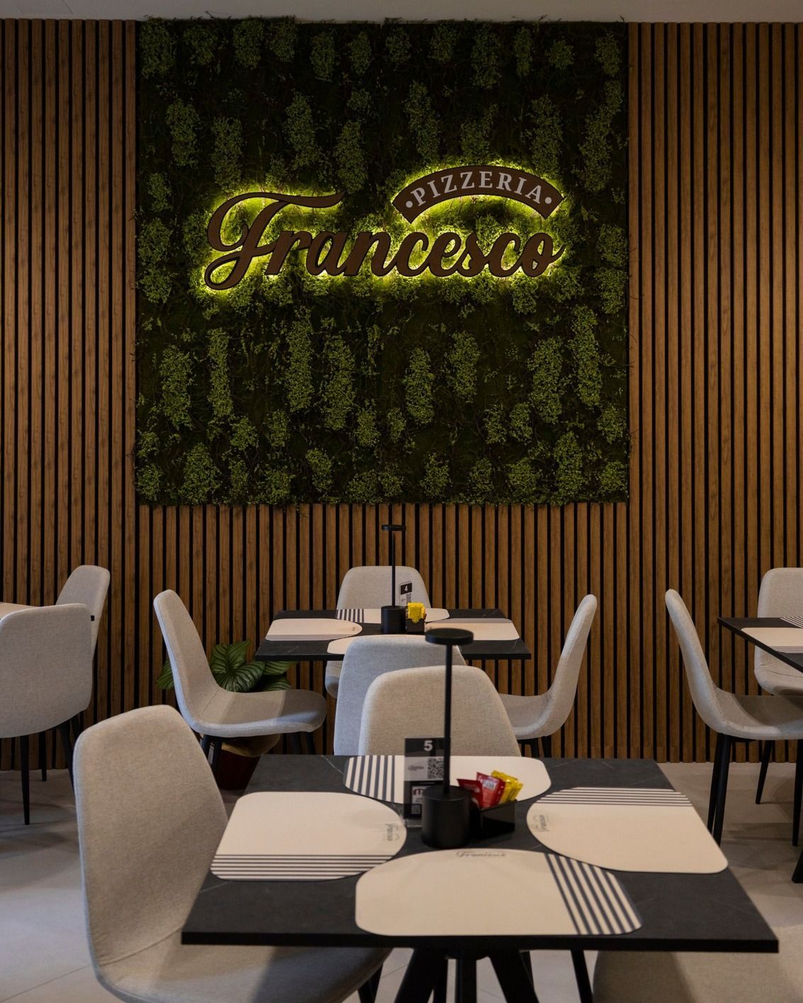 Interno del ristorante con tavoli, sedie e l'insegna 