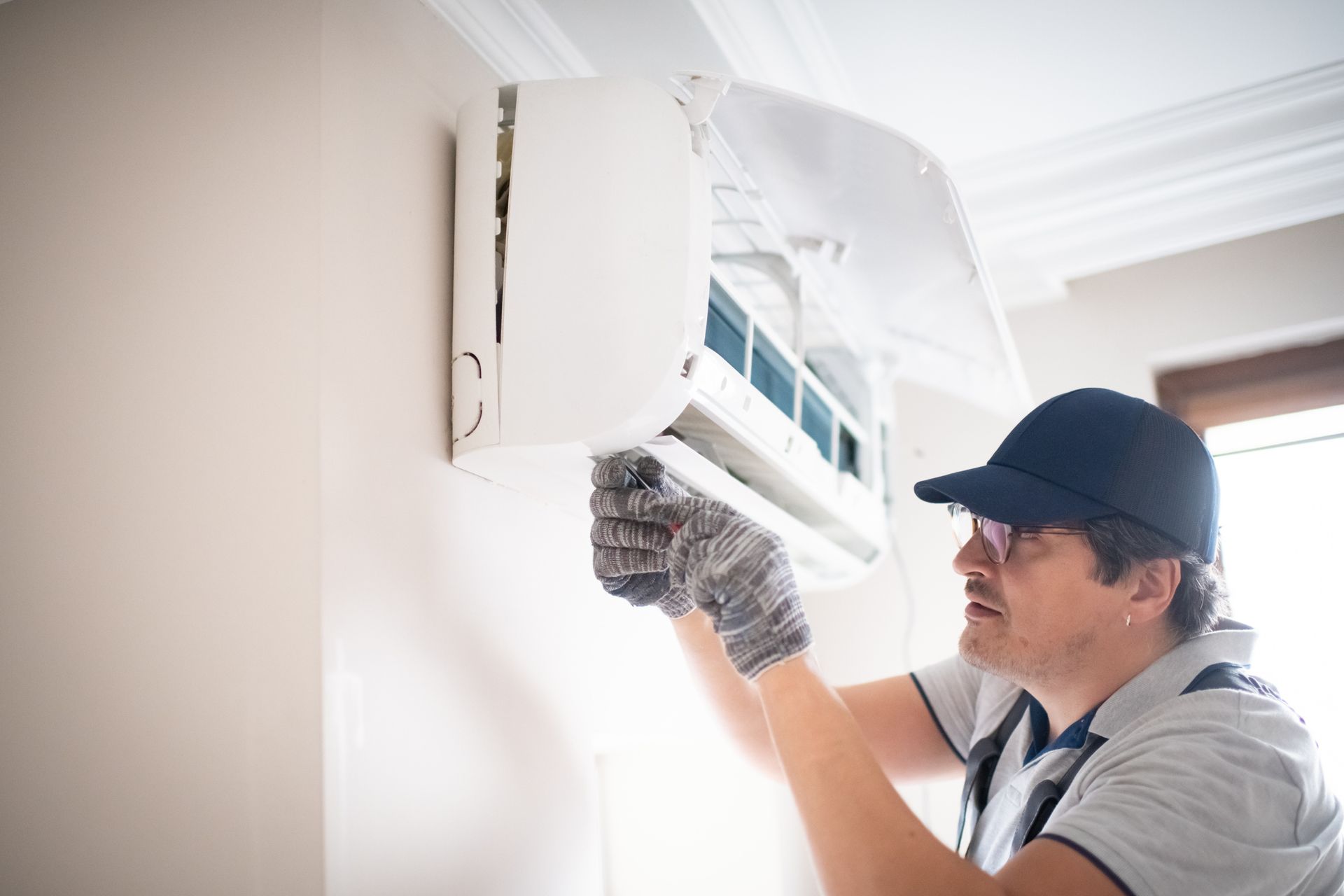Technician wearing glasses performing air conditioning repair as part of a professional AC service.