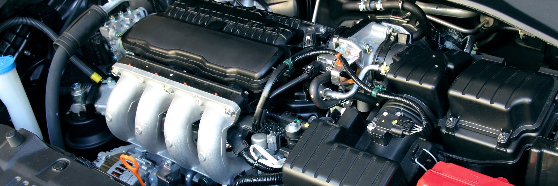 Car engine bay with black components and a silver intake manifold