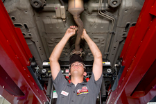 A man is working under a car on a lift.