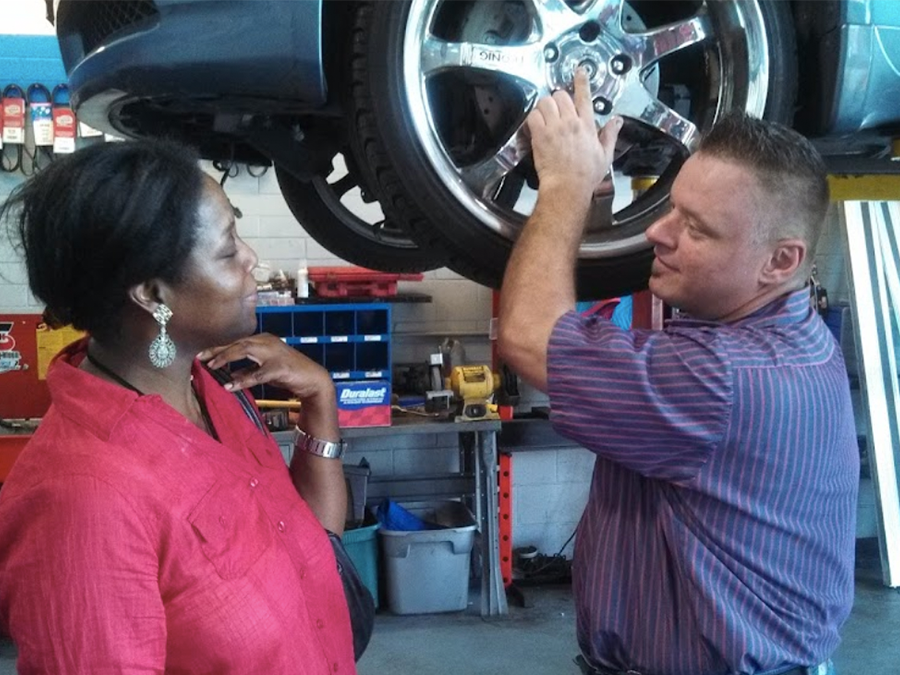 A man and a woman are looking at a tire in a garage