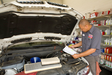A man is working on a car with the hood open in a garage.
