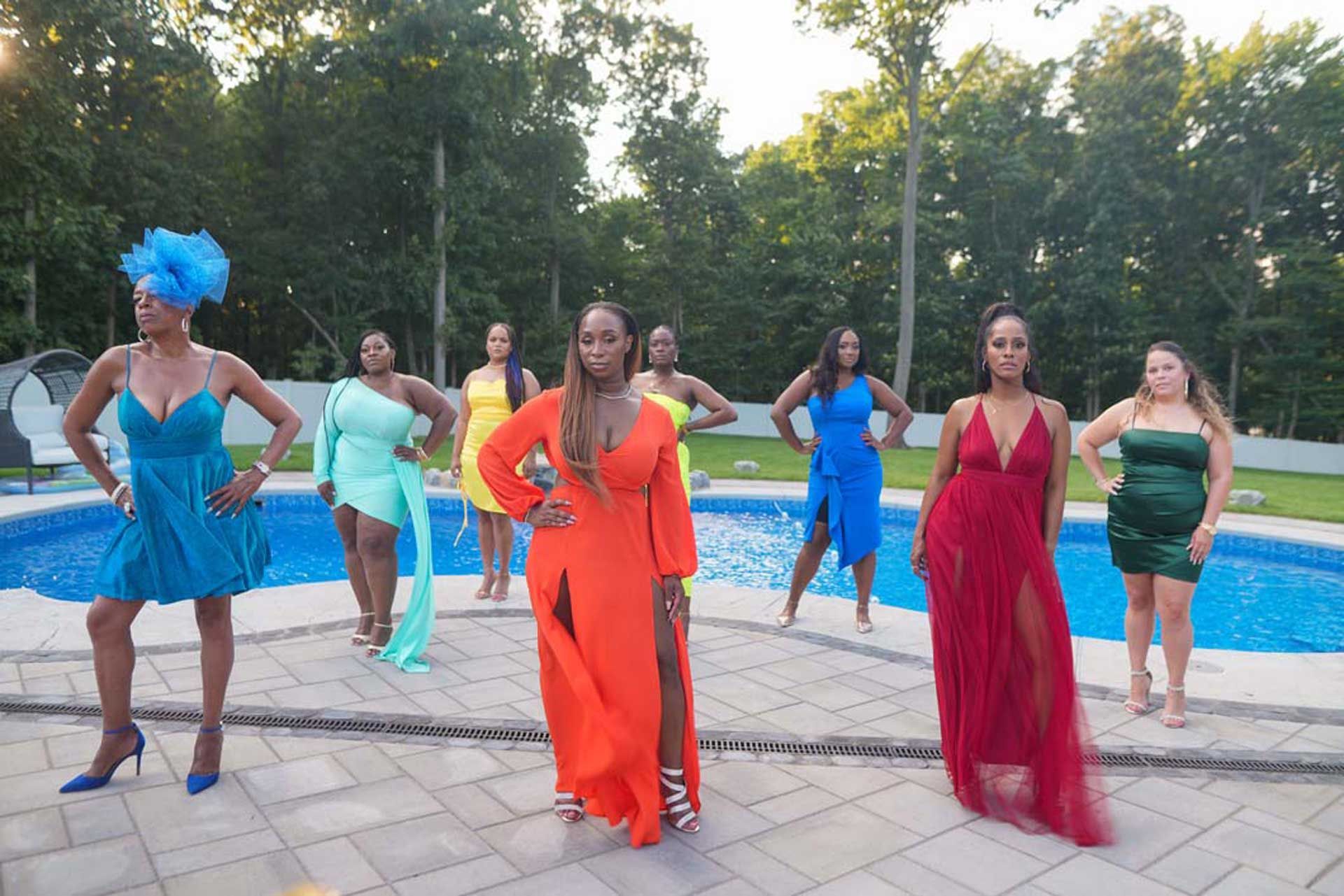 A group of women in colorful dresses are standing next to a swimming pool
