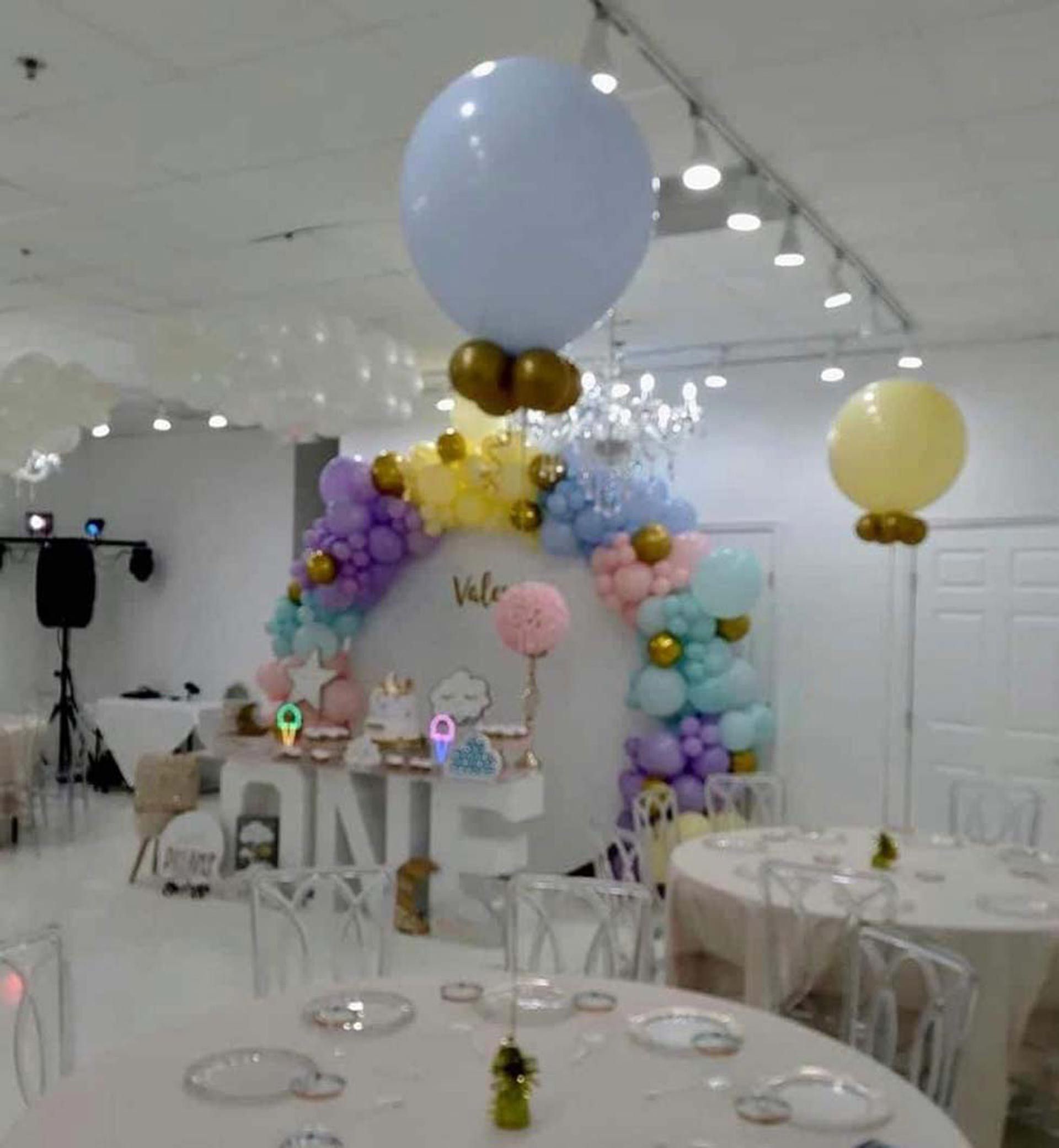 A room with tables and chairs and balloons hanging from the ceiling