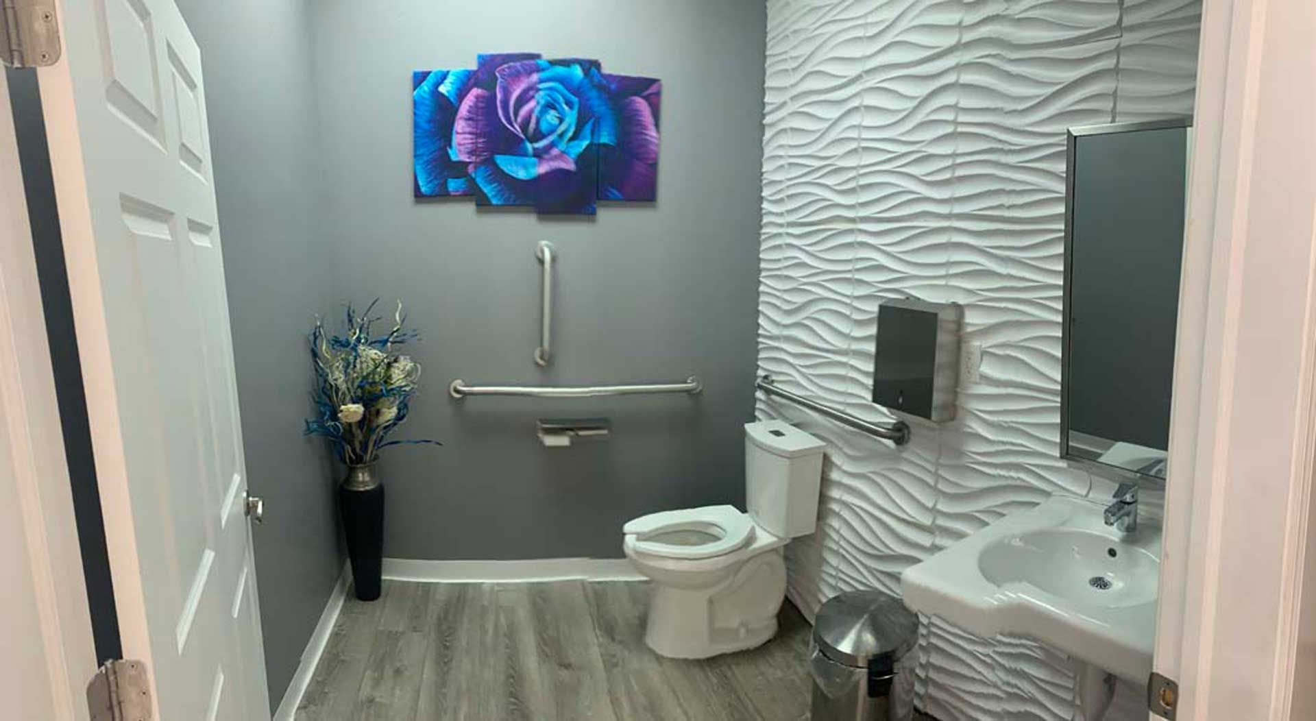A bathroom with a toilet, sink and painting