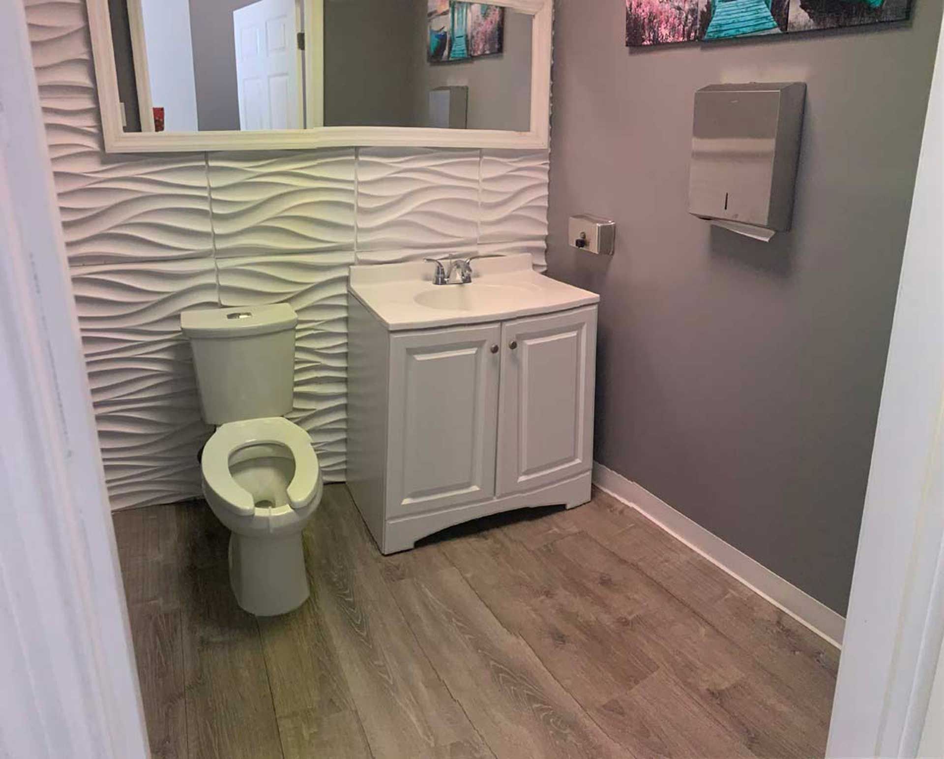 A bathroom with a toilet, sink and mirror