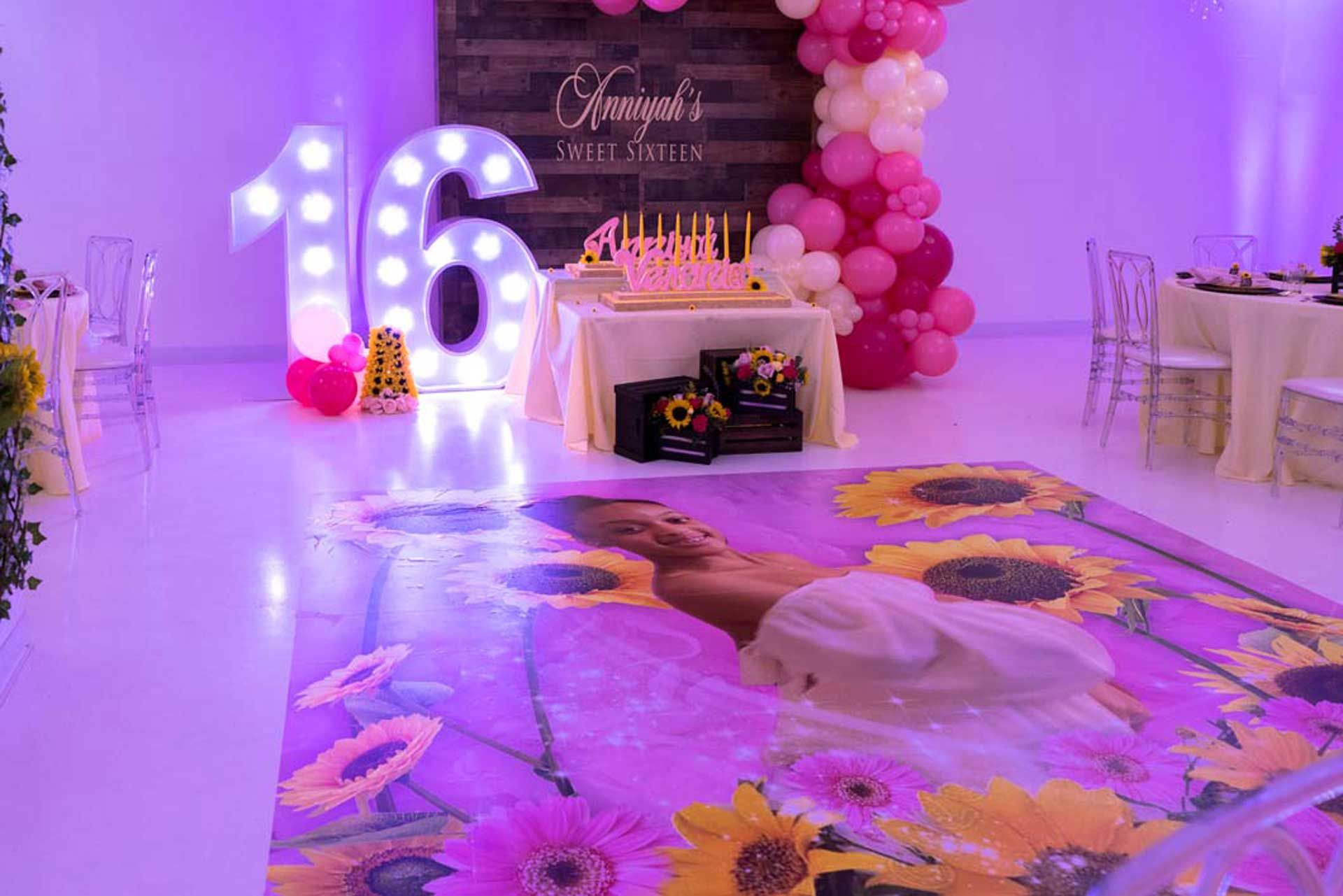 A room decorated for a girl's 16th birthday with balloons, flowers and a dance floor