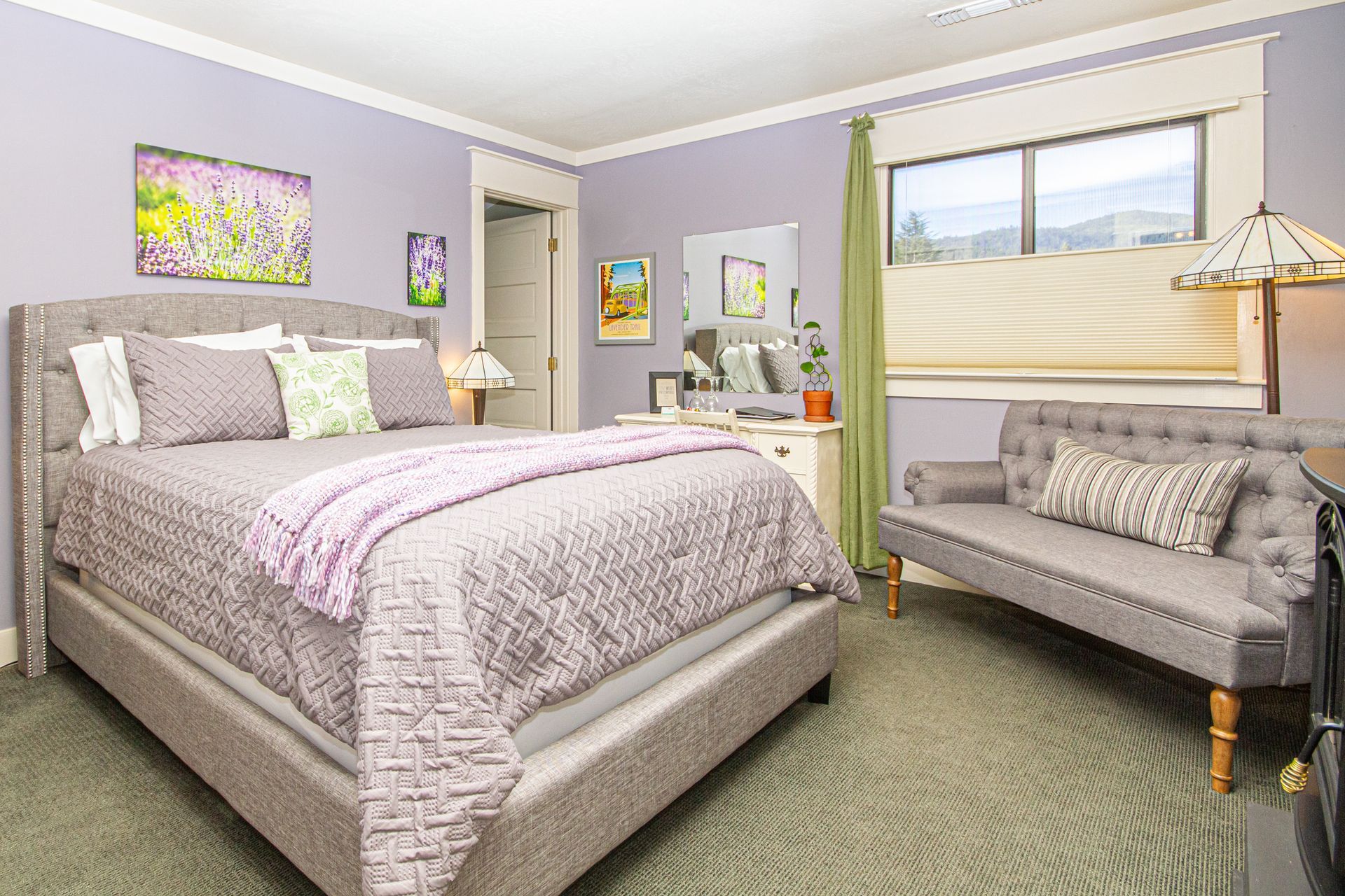 The Lavender Room showing the queen bed, couch, and window.