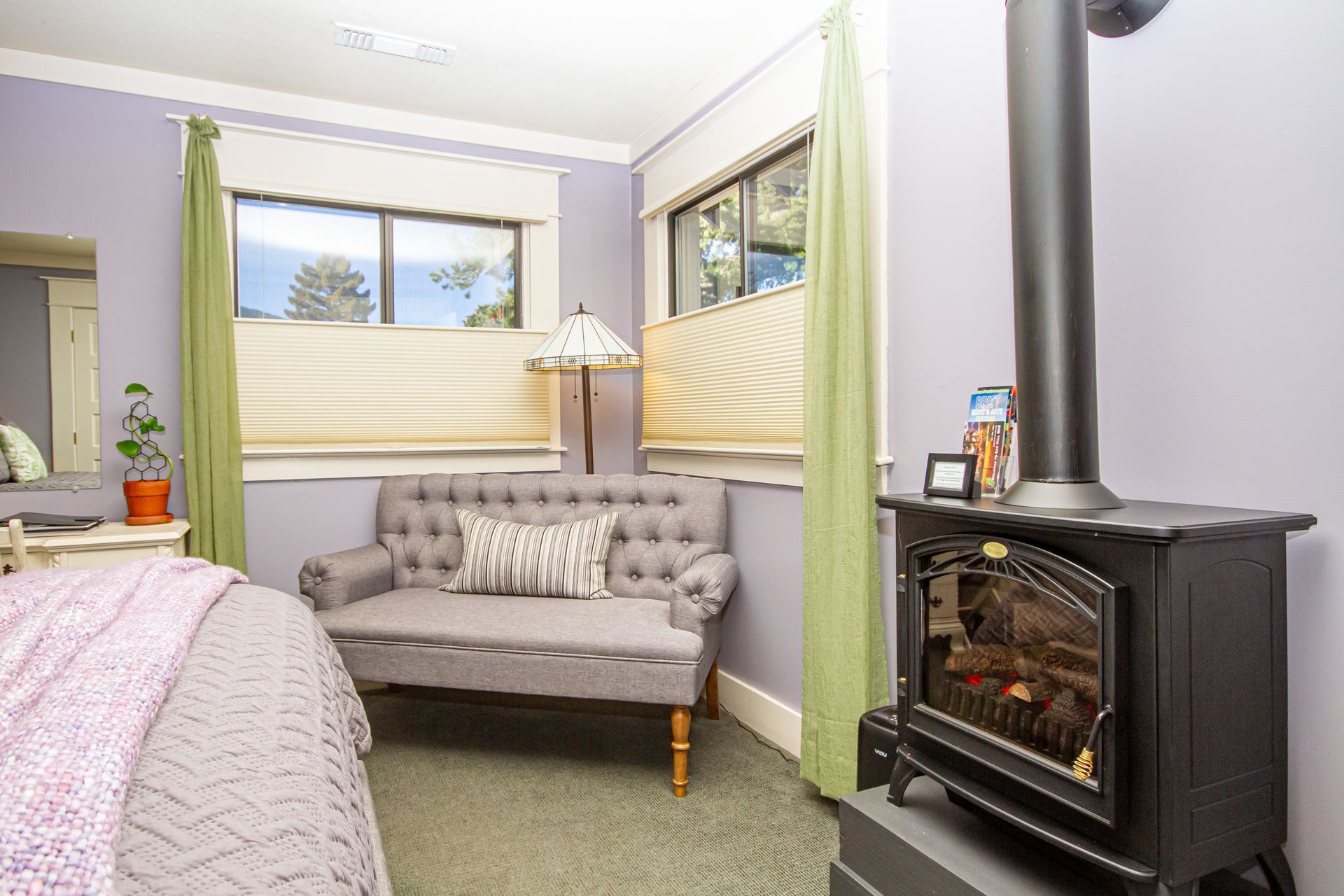 The Lavender Room showing the windows, couch, and electric fireplace.
