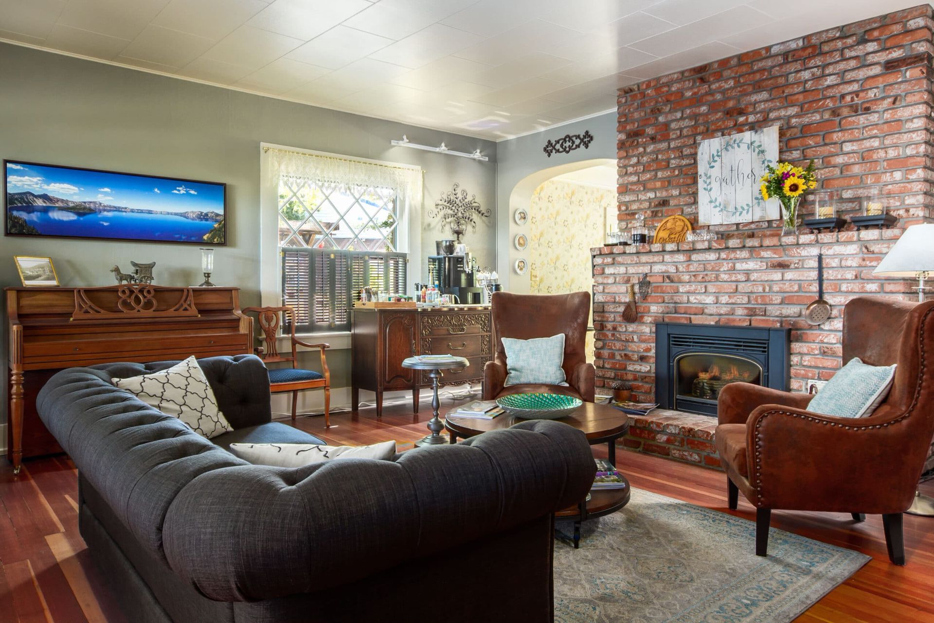 A living room with a couch , chairs , a fireplace and a piano.